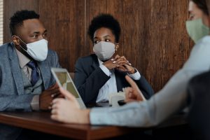 A group of people sitting at a table wearing medical masks