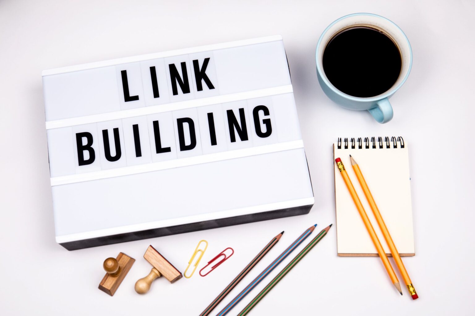 A lettering board that says "link building" next to coffee and other office supplies.